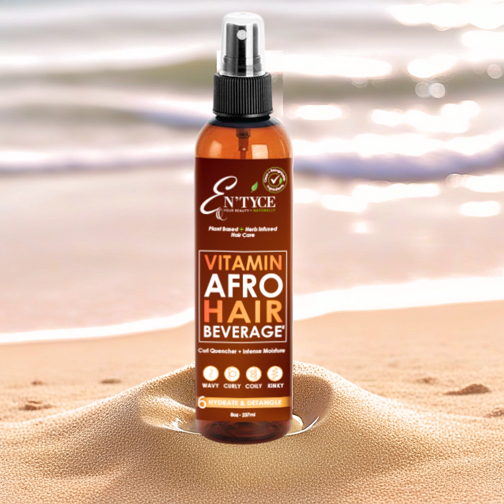 Bottle of En'tyce Vitamin Afro Hair Beverage on a sandy surface with a blurred beach background
