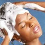Person washing hair with a blue background with En'tyce Your Beauty-Naturally Luxury conditioner