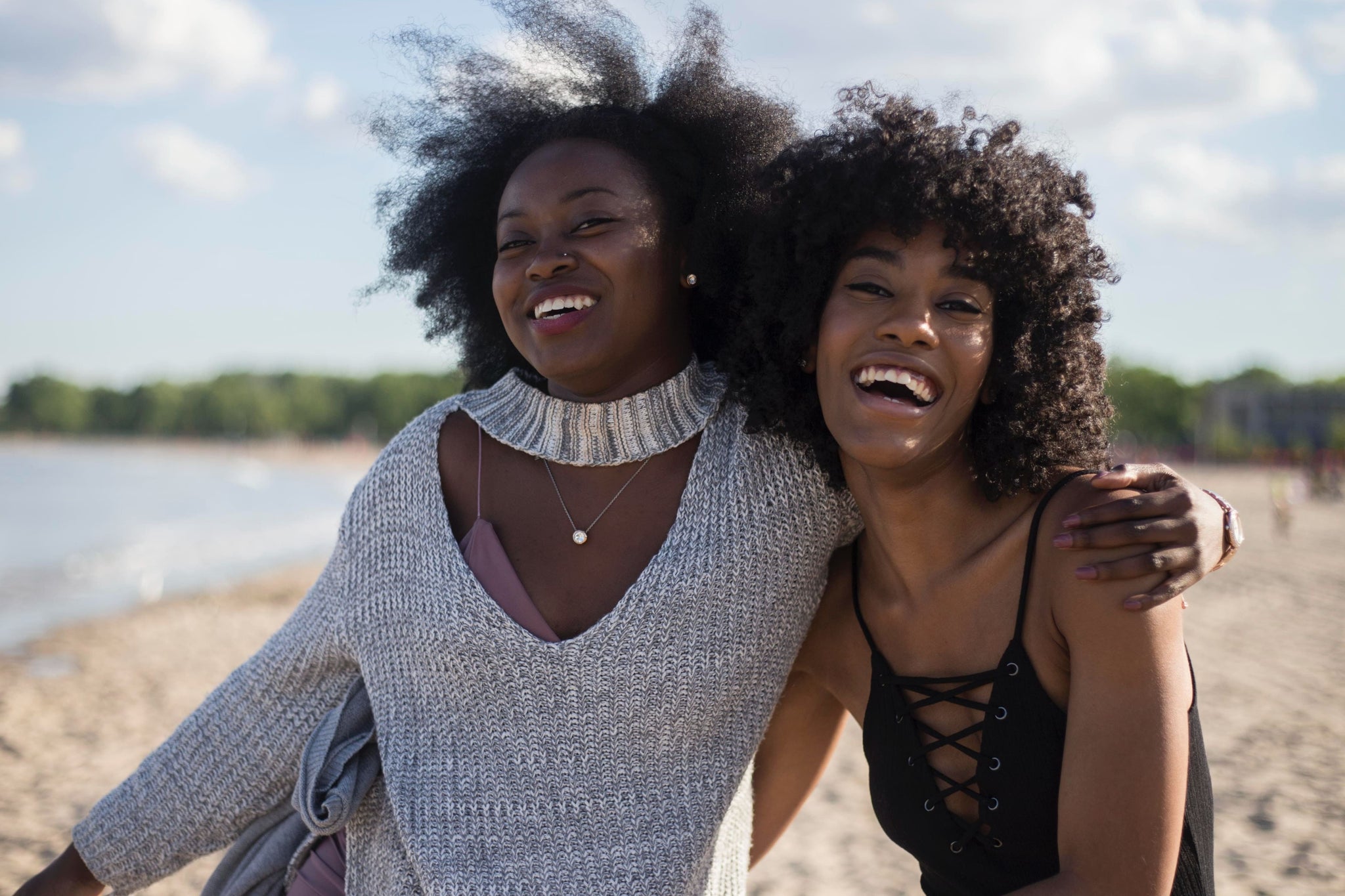 Two women with afro hair laughing on a beach